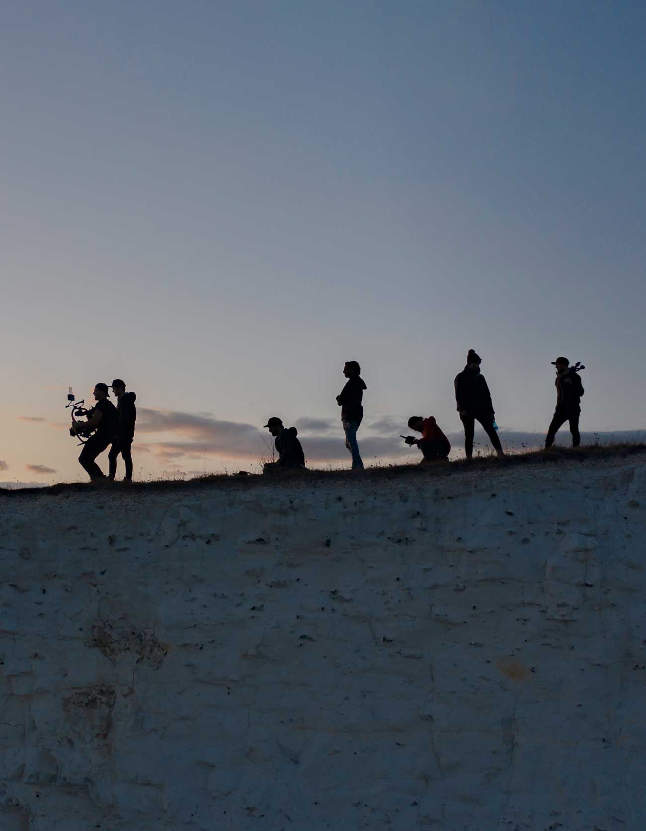 filmcrew silhouettes on a cliff edge drone photo